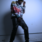 A black male model for JCB ULTRA doing a pose while wearing the city chaos pullover by JCB ULTRA. He is shown holding his glasses while doing a cool pose with a wide stance. 