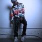 A black male model for JCB ULTRA shown leaning against a wall while wearing the city chaos pullover by JCB ULTRA.