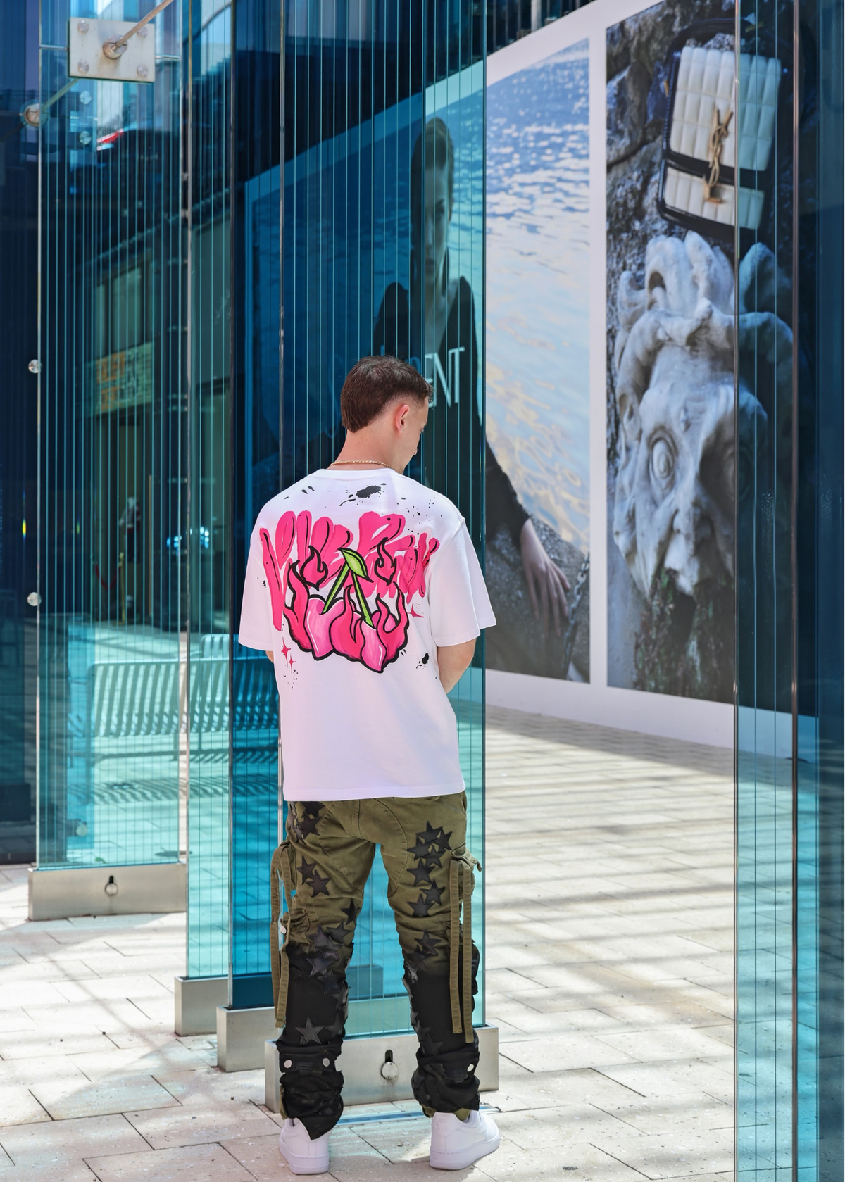 A model shown wearing JCB Ultra love potion tee outside. Showing off the back of the shirt with the iconic love potion graphic 
